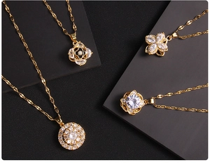 Macro detail of four gold clover necklaces with rotating zircon pendants on black display