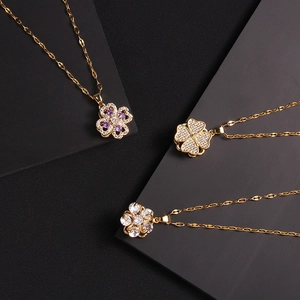 Gold rotating four-leaf clover necklaces with zircon inlays on premium dark display stands