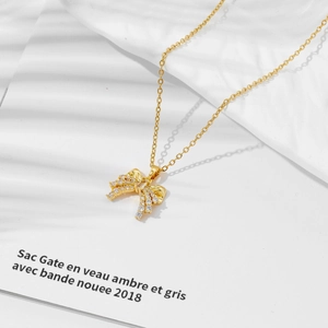Elegant gold bow necklace for women with sparkling pave-set zircons on a white backdrop