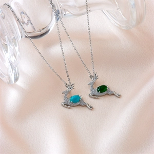 Elegant silver elk pendant necklaces with green and blue stones on silk background