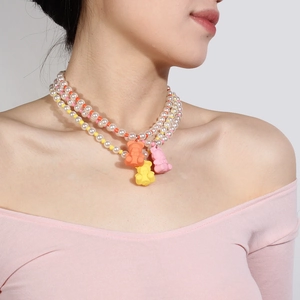 Dreilagige Kunstperlenkette mit bunten Gummibärchen-Anhängern am Hals getragen
