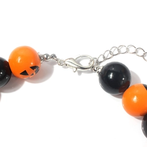 Close-up of Halloween pumpkin beads and black round beads with a silver lobster clasp