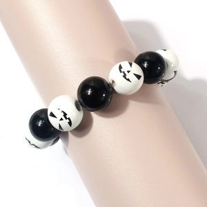 Detail eines Perlenarmbands für Halloween mit schwarzen Perlen und weißen Kürbisgesicht-Mustern
