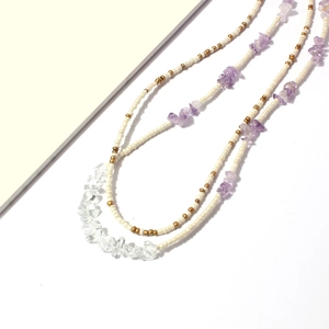Chaîne de corps bohème avec pierres de cristal violettes et perles sur fond blanc