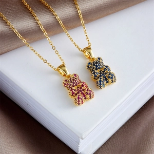 Colorful bear pendant necklaces in gold with pink and blue crystals on satin background