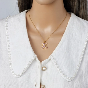 Vergulde beer hanger ketting met roze zirkoon stenen op een model met een kant blousje