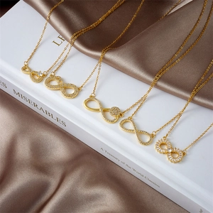 Collares con símbolo de infinito dorados con circonitas sobre fondo de seda marrón