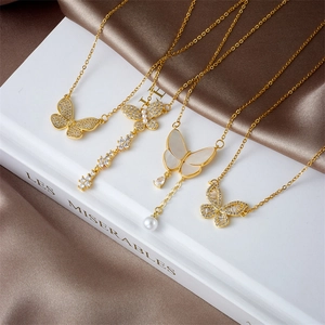 Set de collares de mariposa dorados con circonitas y perlas sobre fondo de seda