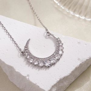 Elegant silver crescent moon necklace with micro-p鑲嵌ed zircons on a white stone background