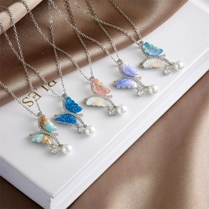 Collares de mariposas de colores con colgantes de perlas sobre un fondo de seda elegante
