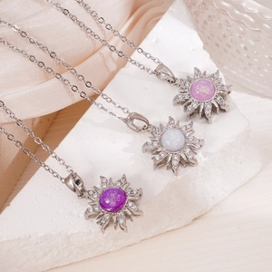 Tres collares con colgante de sol dorado con ópalo y circonitas sobre piedra blanca