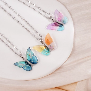 Tres collares de mariposa coloridos en resina con pan de oro y circonitas en mármol