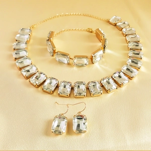 Detailed close-up of golden rhinestone jewelry set with emerald-cut crystals on silk