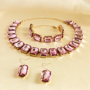 Detailed set of pink gemstone necklace, bracelet and earrings on gold setting
