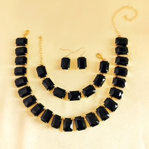Close-up of rhinestone necklace set with black rectangular gems and golden finish
