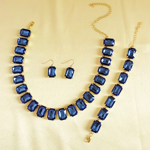 Detail view of gold-tone jewelry set featuring emerald-cut navy blue rhinestones