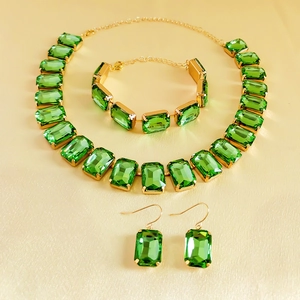 Detailed close-up of emerald green rhinestone jewelry set with gold plated finish