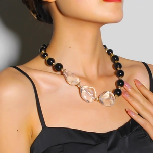 Primo piano di una collana con grandi cristalli trasparenti e perline nere su una modella