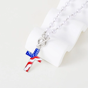 Detail van kruishanger met Amerikaanse vlagpatroon en witte parelketting met OT-sluiting