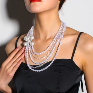 Détail d'un collier de perles multicouche orné d'une fleur en strass sur une robe noire