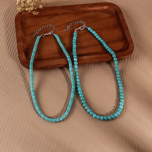 Minimalist turquoise beaded necklace set with flat disc and round stone beads in a wooden tray