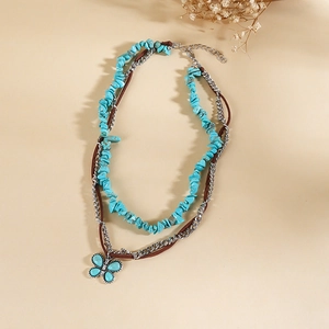 Détail macro du pendentif papillon bohème avec pierres turquoises sur cordon cuir