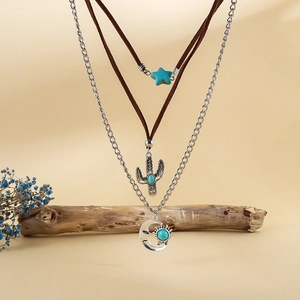 Detalle de collar bohemio de capas con dijes de cactus turquesa, sol y luna sobre madera