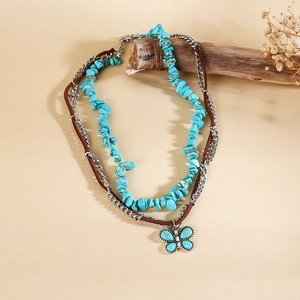 Détail d'un pendentif papillon turquoise sur un collier à plusieurs rangs en cuir