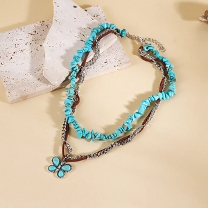 Détail d'un collier bohème multicouche avec pierres turquoise et pendentif papillon argenté