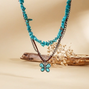 Détail d'un collier bohème multicouche avec pierres turquoise et pendentif papillon