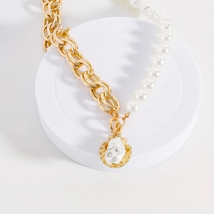 Dettaglio della collana in catena d'oro e perle con ciondolo a conchiglia e strass lucidi