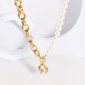 Dettaglio ravvicinato di una collana di perle e catena dorata con ciondolo a forma di conchiglia