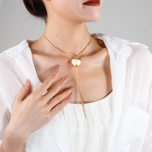 Dettaglio della collana con ciondolo a cuore e catena d'oro su camicetta bianca