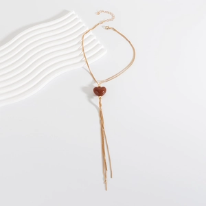 Dettaglio della collana a catena serpente dorata con ciondolo a cuore marrone e nappe