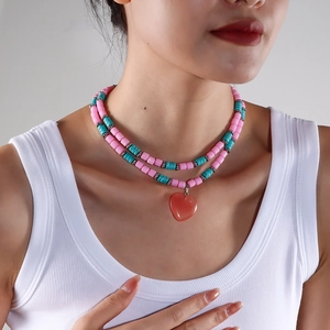Close-up of double-layered beaded necklace with turquoise beads and red heart pendant