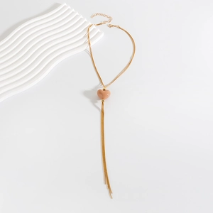 Dettaglio della collana a nappa dorata con pendente a cuore rosa e catena allungabile