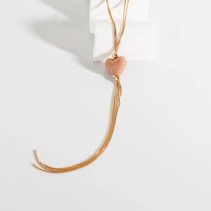 Dettaglio pendente a cuore in resina rosa con nappe in catena a serpente dorata su base