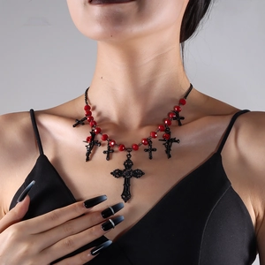 Macro detail of red beaded gothic necklace with vintage black cross pendants on a model
