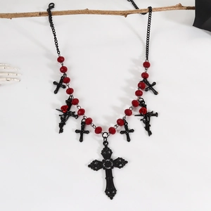 Gothic black cross necklace with red beads and roses displayed on a withered branch