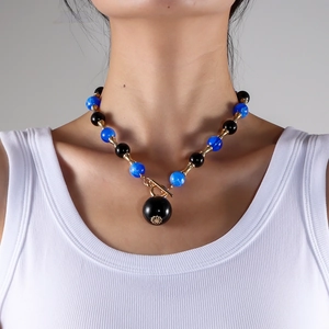 Détail du collier de perles marbrées bleues avec pendentif noir et fermoir à bascule doré