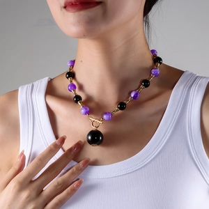Détail du collier de perles oeil-de-chat mauves, perles noires et fermoir à bascule doré
