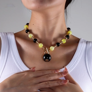 Détail du collier de perles noires et jaunes translucides sur le cou du mannequin