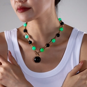 Détail du collier de perles vertes et noires avec connecteurs bambou dorés et fermoir OT