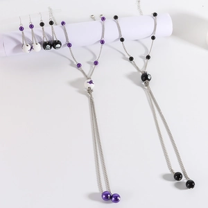Detailed view of Halloween necklace with purple bats, skulls and elegant long beaded tassels