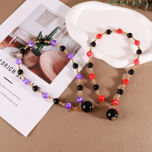 Détail du collier de perles avec entretoises dorées en bambou et grand pendentif boule noire