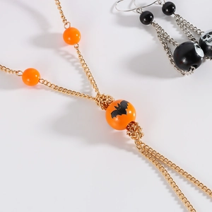 Detail of Halloween jewelry set with orange bat necklace and skull tassel earrings