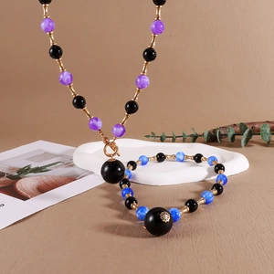 Détail d'un ensemble de bijoux vintage avec perles violettes et accents en forme de bambou