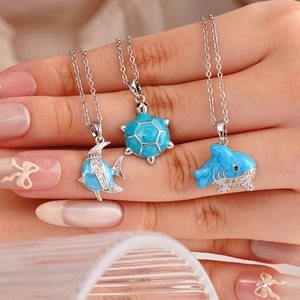 Collane marine con tartaruga e delfino in smalto blu e zirconi mostrate sulla mano