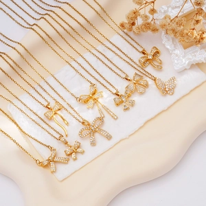 Elegant gold bow necklace set with cubic zirconia pendants on a white wave tray
