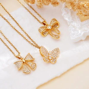 Elegant gold bow and butterfly pendant necklace set with zircon inlay on white fabric